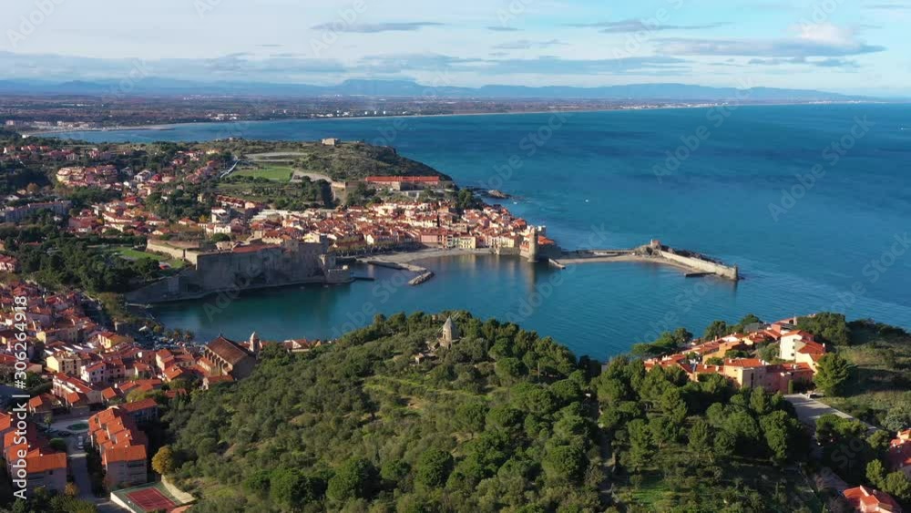 Old windmill in Collioure aerial view of the city France green trees and blue sea Old windmill in Collioure aerial view of the city France green trees and blue sea