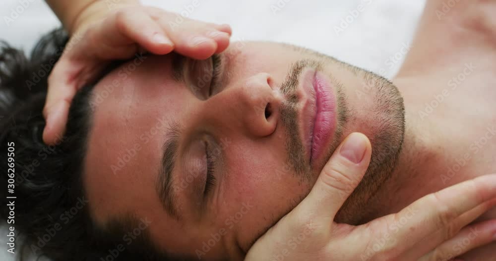 Close up of an young handsome man is receiving a facial massage and spa treatment for perfect skin in a luxury wellness center.