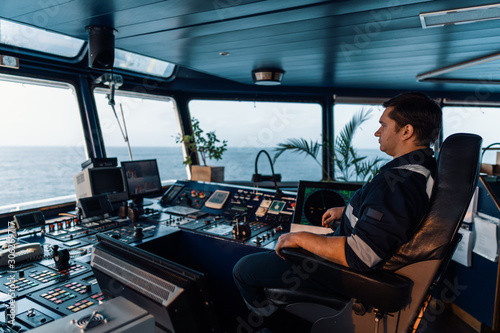 Marine navigational officer during navigational watch on Bridge . Work at sea photo