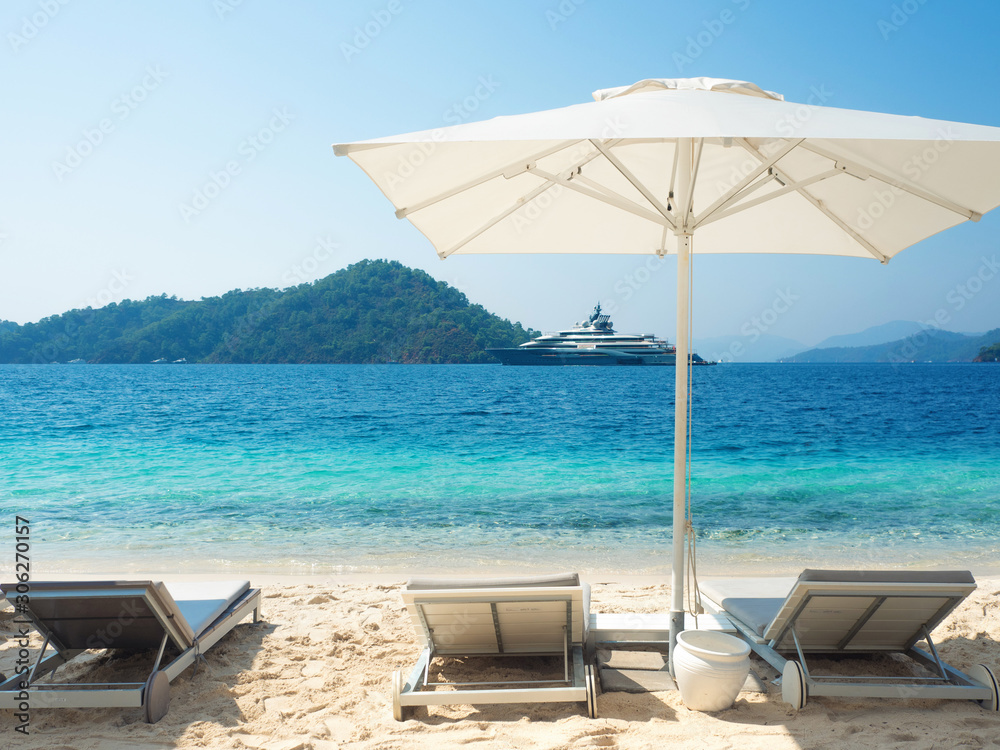 Three sun loungers and one parasol on the beach. The beach with white sand