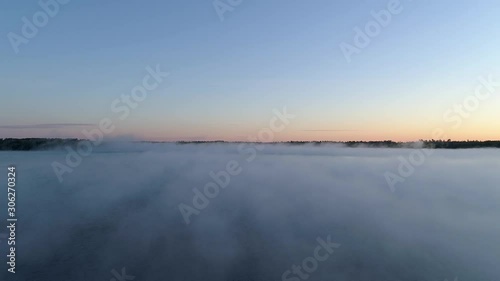 4K aerial reverse flight over a fog covered lake on a misty fall morning in Northwest Ontario, Canada.