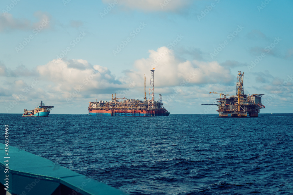 FPSO tanker vessel near Oil Rig platform. Offshore oil and gas industry. Flare is burning with smoke. View from supply vessel FPSO tanker vessel near Oil Rig platform. Offshore oil and gas industry. Flare is burning with smoke. View from supply vessel