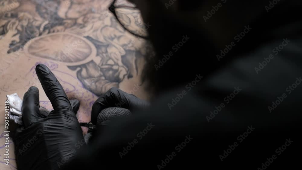 Professional tattoo artist showing the process of doing tattoo on back Professional tattoo artist showing the process of doing tattoo on back