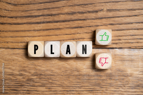 wooden blocks with word "plan" and decision between thumb up or thumb down