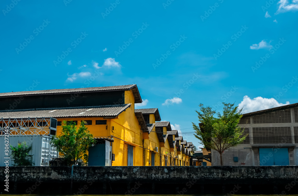Vintage style warehouse building with blue sky and white clouds. Yellow warehouse for storage of goods. Exterior building. Vintage style architecture. Retro concrete office and warehouse building.