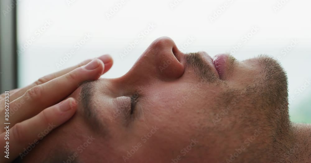Close up of an young handsome man is receiving a facial massage and spa treatment for perfect skin in a luxury wellness center. Close up of an young handsome man is receiving a facial massage and spa treatment for perfect skin in a luxury wellness center.