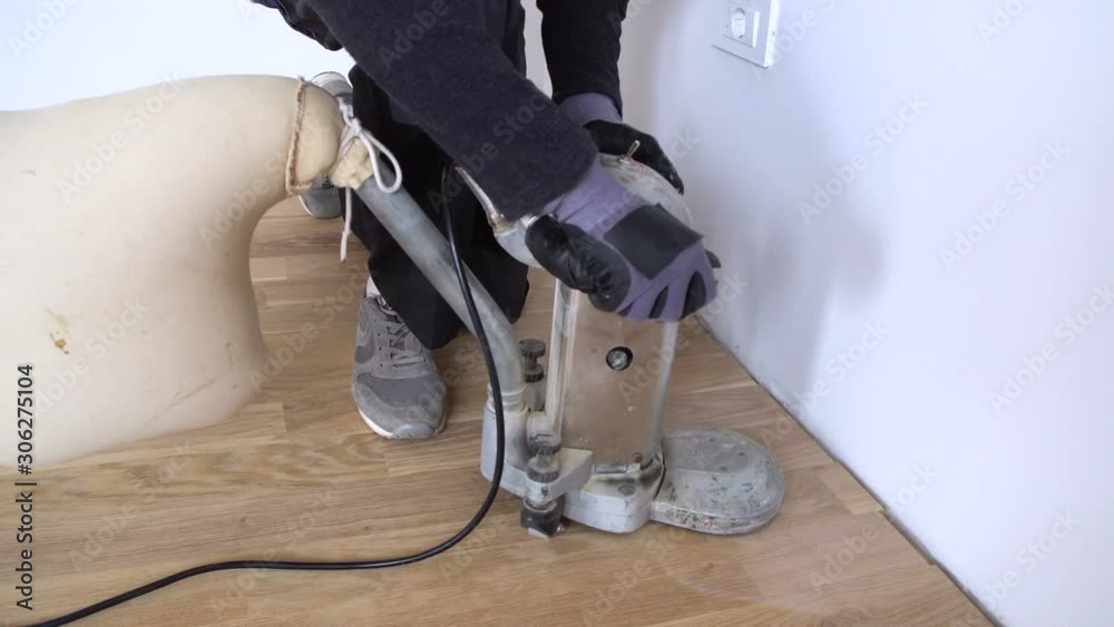 Scraping floor surface with grinding machine. Repair in the apartment
