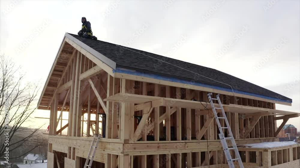 Aerial panoramic view of tiler in safety harness finishing roof ridge. Works at height Aerial panoramic view of tiler in safety harness finishing roof ridge. Works at height