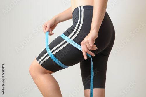 Woman measure her legs with tape measure. Control of weight. Result of fitness and diet.
