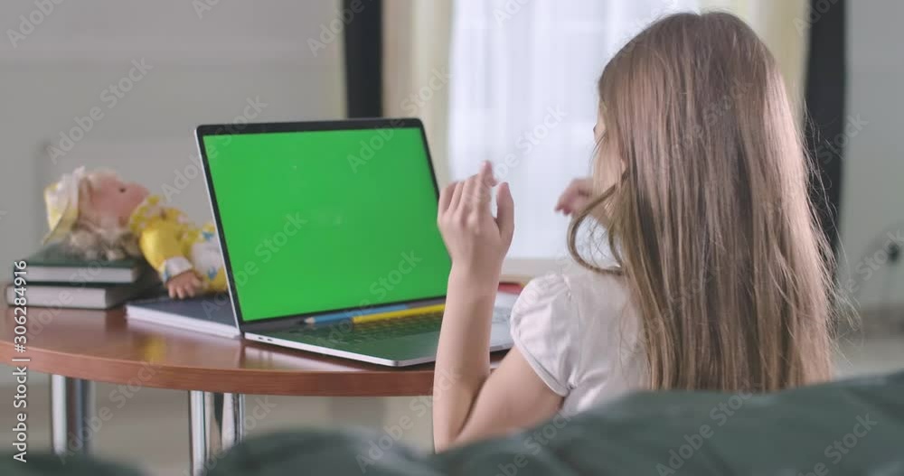 Cute Caucasian girl sitting in front of chromakey laptop screen and talking. Schoolchild studying online or using social media or watching movie or cartoon. E-learning, internet. Cinema 4k ProRes HQ. Cute Caucasian girl sitting in front of chromakey laptop screen and talking. Schoolchild studying online or using social media or watching movie or cartoon. E-learning, internet. Cinema 4k ProRes HQ.