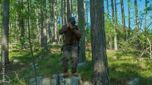 A happy and smiling photographer clicking some amazing shots with his DSLR amidst dense green forest.Slow motion. photo