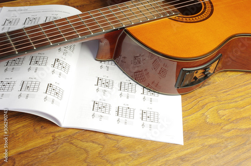 Acoustic guitar and chord book on a wooden texture