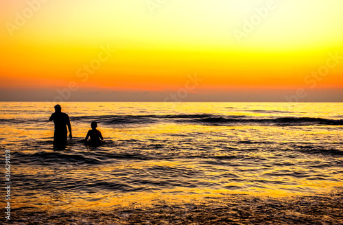man stood by the sea with his familyin and watched the sun rise in the morning. He looked happy and warm    © pcbang