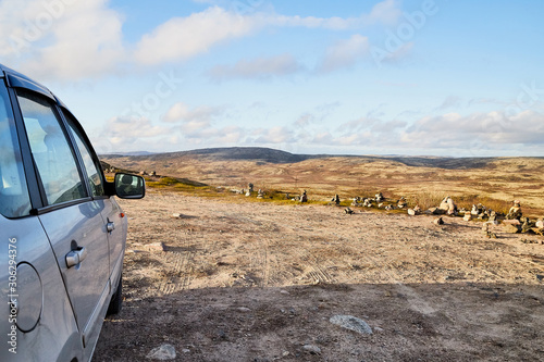Tundra landscape with moss, glass and stouns in the north of Norway or Russia, blue sky with clouds and car