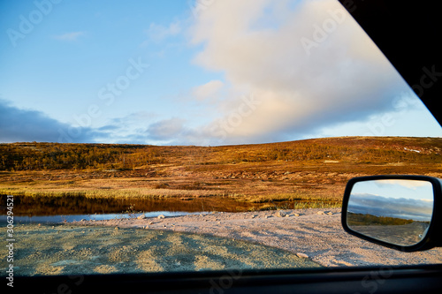 Tundra landscape with moss, glass and stouns in the north of Norway or Russia and blue sky with clouds frought window of a car photo