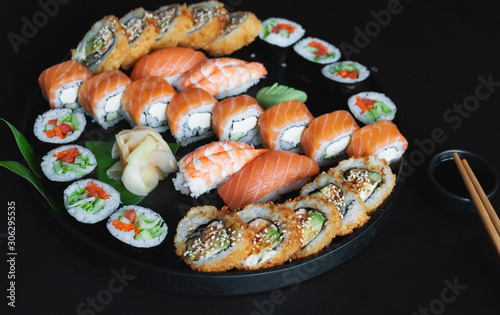  Various classic sushi and rolls from fresh ingredients over black background. Japanese cuisine.