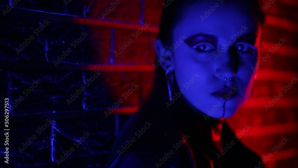 Portrait of a girl in a cyberpunk costume in neon colorful light. Glowing sword and contact lenses. Portrait of a girl in a cyberpunk costume in neon colorful light. Glowing sword and contact lenses.