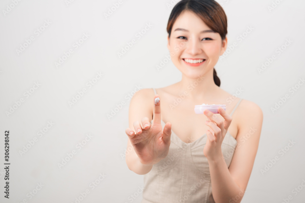 Cheerful young woman applying face cream isolated on white Cheerful young woman applying face cream isolated on white