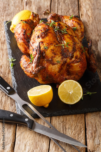 Homemade chicken rotisserie with thyme, lemon closeup on a slate board. vertical