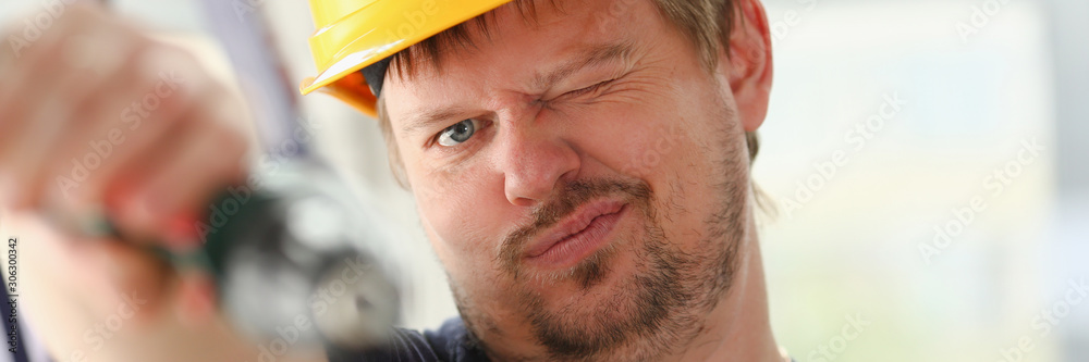 Obraz premium Arms of worker using electric drill closeup