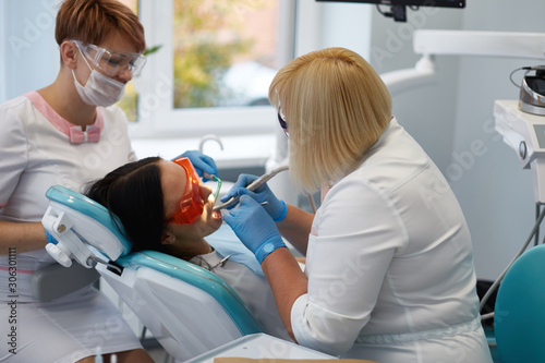 Doctor dentist treats teeth of a beautiful young girl patient.