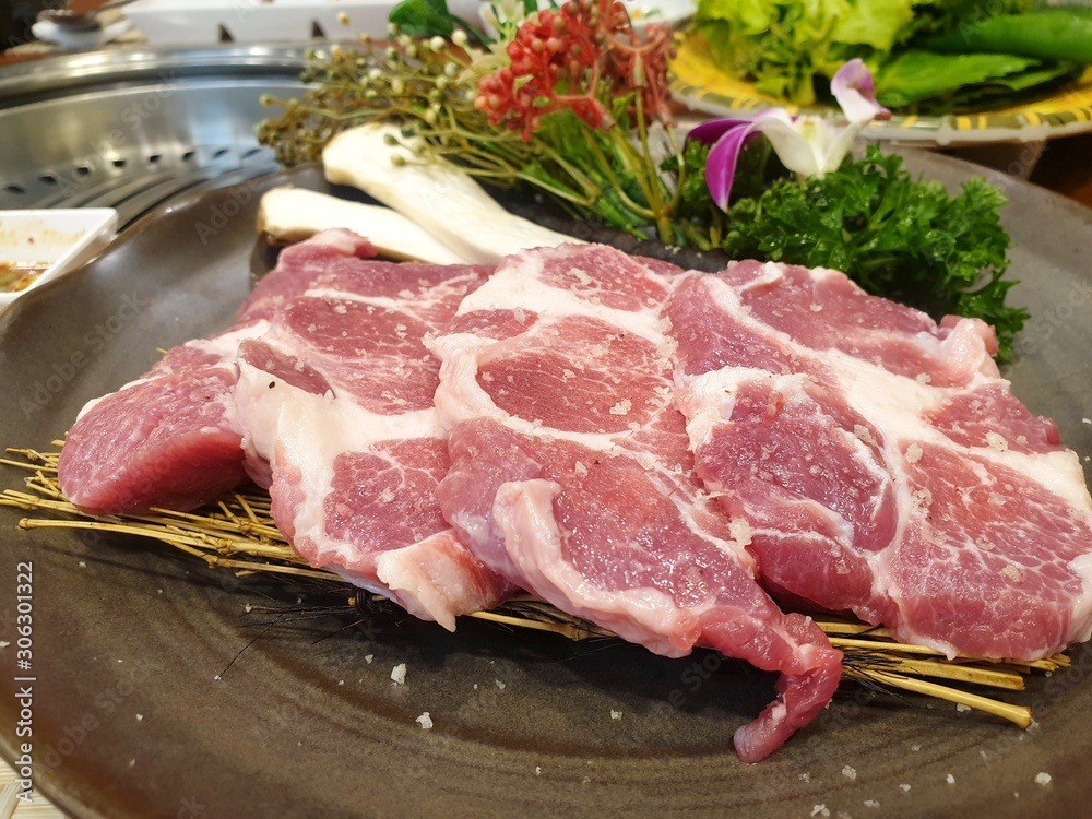 Top view of pork collar or kurobuta on dry bamboo leaves on black dish as a background in restaurant at Thailand, fresh meat for grill