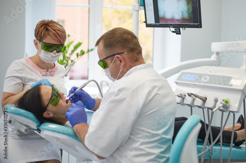 Doctor dentist treats teeth of a beautiful young girl patient.