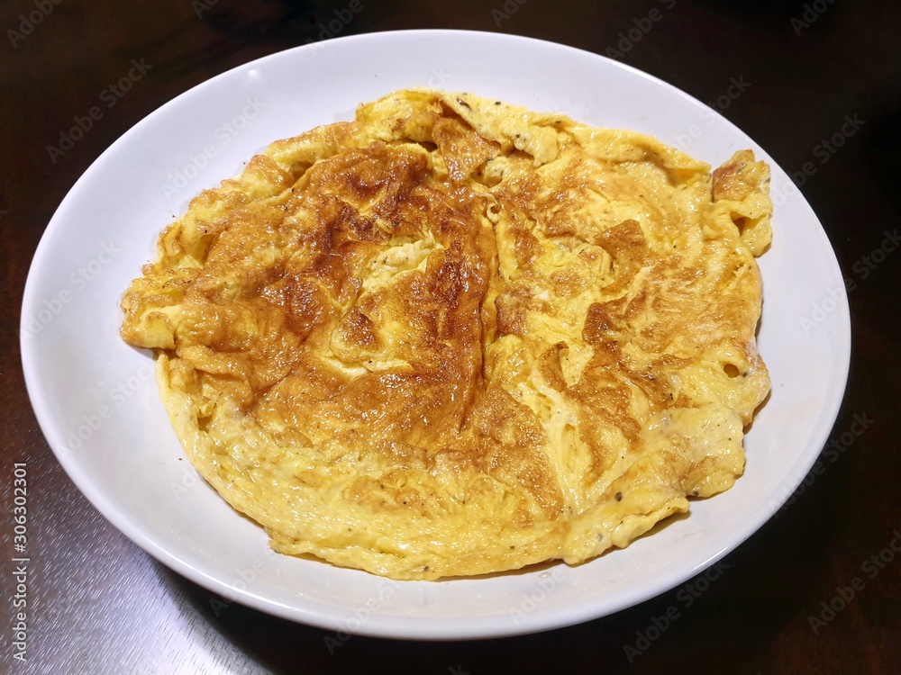 Top view of omelet in white plate on wooden table as a background, Space for text in template, Ready to eat Top view of omelet in white plate on wooden table as a background, Space for text in template, Ready to eat
