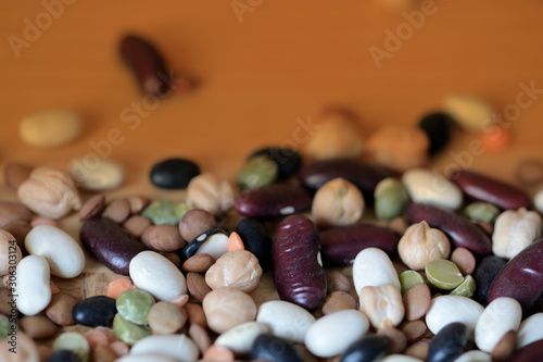 Different beans scattered on a wooden surface close-up. Naturel organic food background