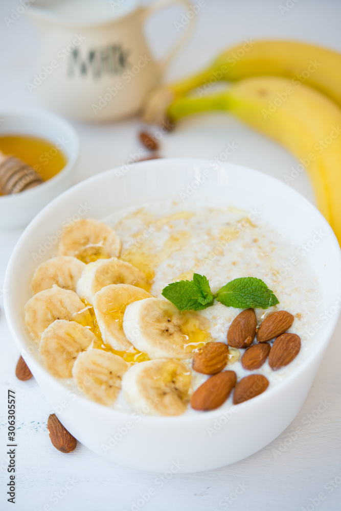 Oatmeal with honey, banana and nuts in a plate on a white background. Oatmeal with honey, banana and nuts in a plate on a white background.