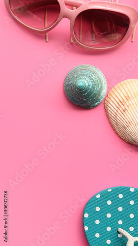 Sunglasses and sandals with seashell on pink background