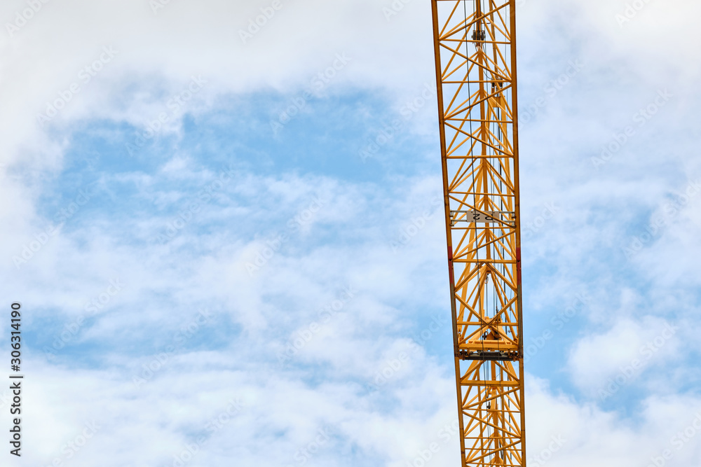 Background with closeup of yellow crane arm against a blue sky with clouds. Seen in on a construction site in Bavaria, Germany in September. Background with closeup of yellow crane arm against a blue sky with clouds. Seen in on a construction site in Bavaria, Germany in September.