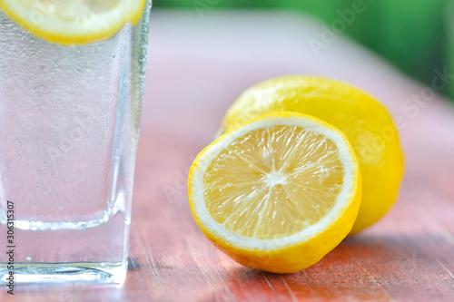 A glass of lemonade and cut lemon on a red table