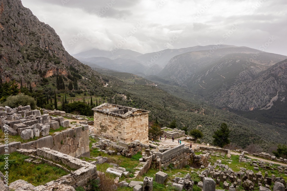 The landscape of ancient Delphi in Greece with Treasury of Athenians and cloudy weather