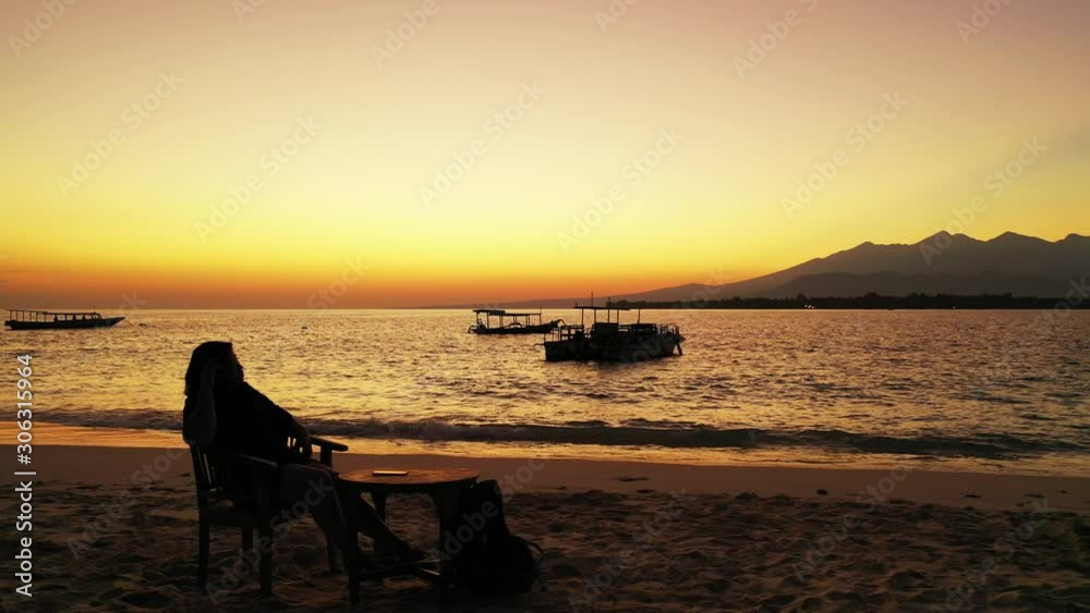 Silhouette of the tourist in the beach bar enjoying majestic sunset on the tropical beach. Silhouette of the tourist in the beach bar enjoying majestic sunset on the tropical beach.