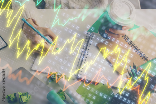 Financial forex graph displayed on hands taking notes background. Concept of research. Multi exposure