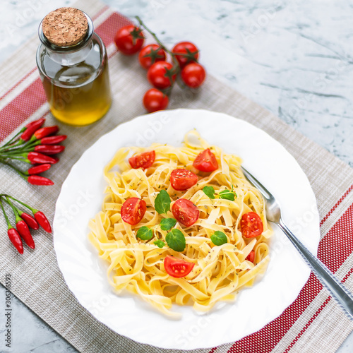 Spaghetti with cherry tomatoes and mint on a white plate, top view