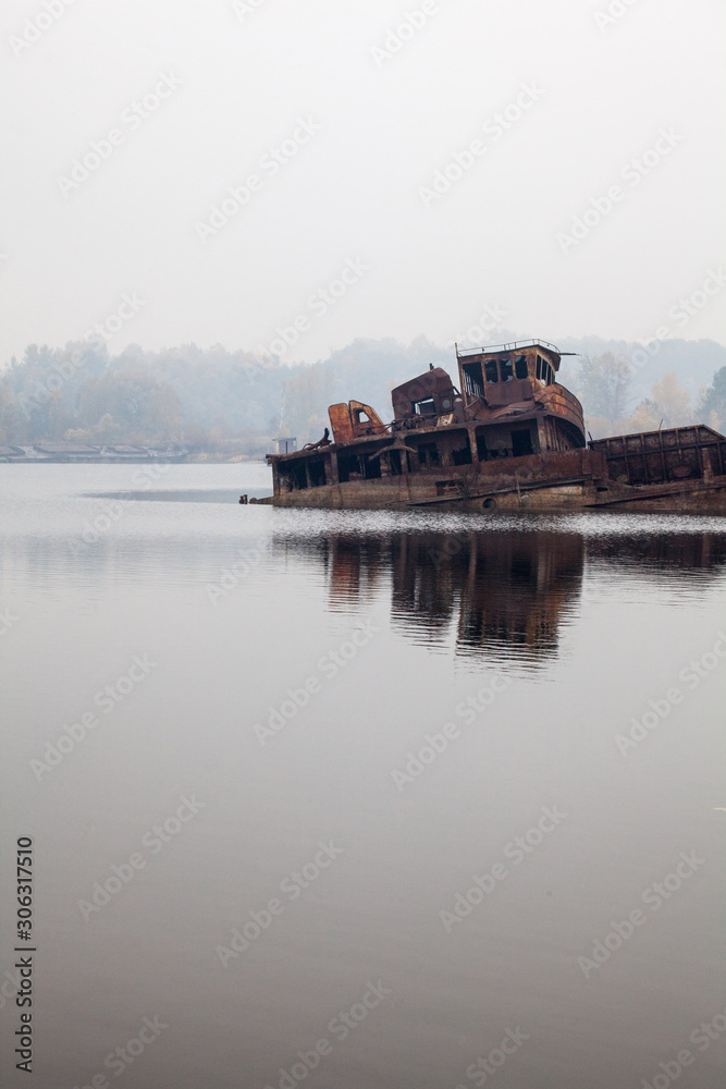 Old sunken ship in water in a foggy day
