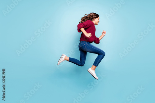 Full length body size photo of curly wavy cheerful trendy preteen wearing jeans denim burgundy sweater running jumping towards shopping mall isolated vivid blue color background