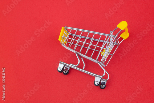 Yellow shopping cart or trolley on red background