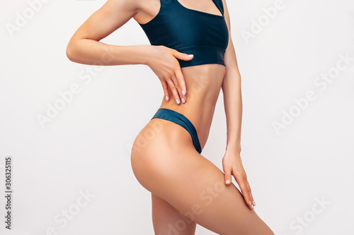 Unrecognizable fit woman in black lingerie on white background isolated. Muscular slim attractive female with flat belly. Copy space for text. Body care, healthy and sporty life, hair removal concept