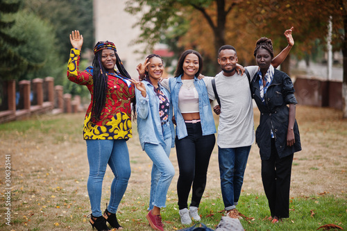 Fototapeta Naklejka Na Ścianę i Meble -  Row of group five african college students spending time together on campus at university yard. Black afro friends studying. Education theme.