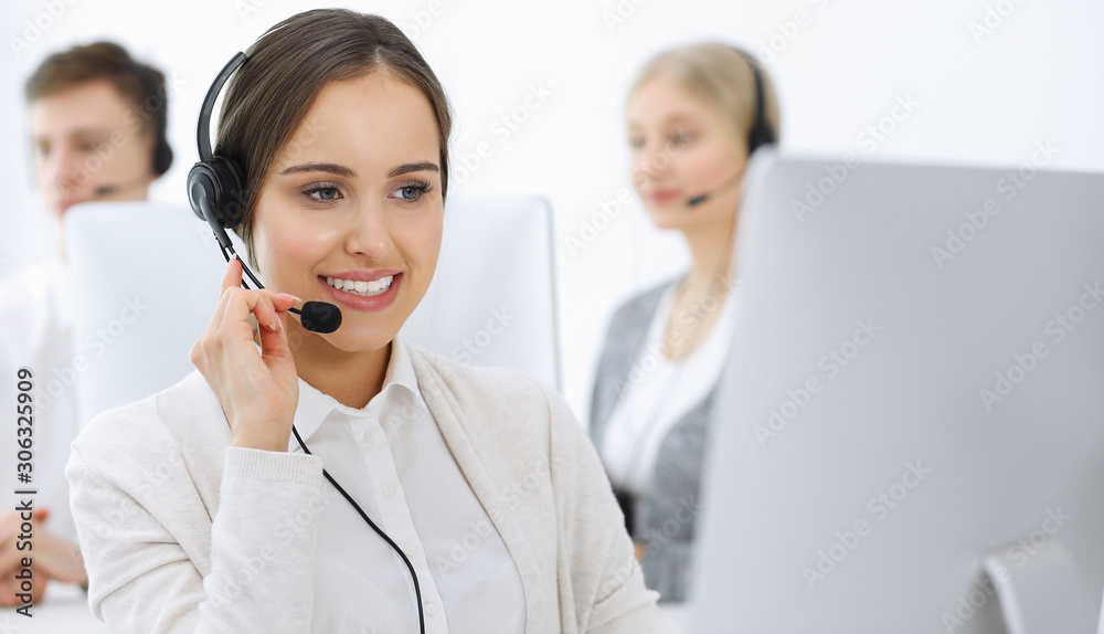 Call center. Group of operators at work. Focus on beautiful woman receptionist in headset at customer service white colored office. Business concept Call center. Group of operators at work. Focus on beautiful woman receptionist in headset at customer service white colored office. Business concept