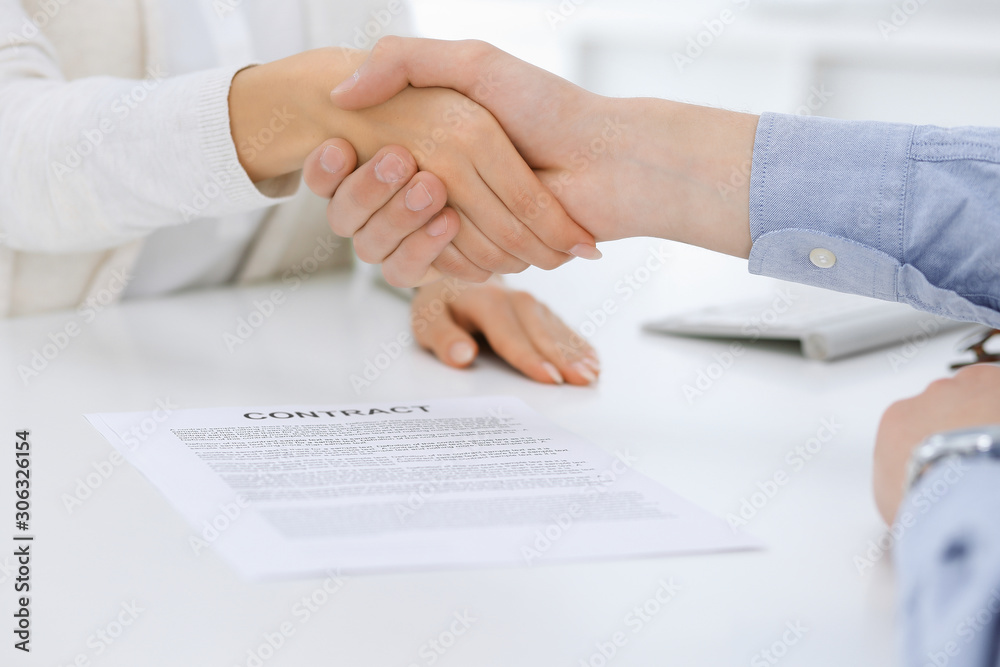 Business people shaking hands at meeting or negotiation after contract discussing. Businessman and woman handshake at office while sitting at the desk. Success concept Business people shaking hands at meeting or negotiation after contract discussing. Businessman and woman handshake at office while sitting at the desk. Success concept