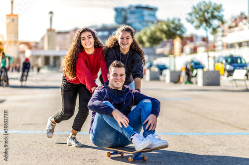 Three friends playing with a skate board