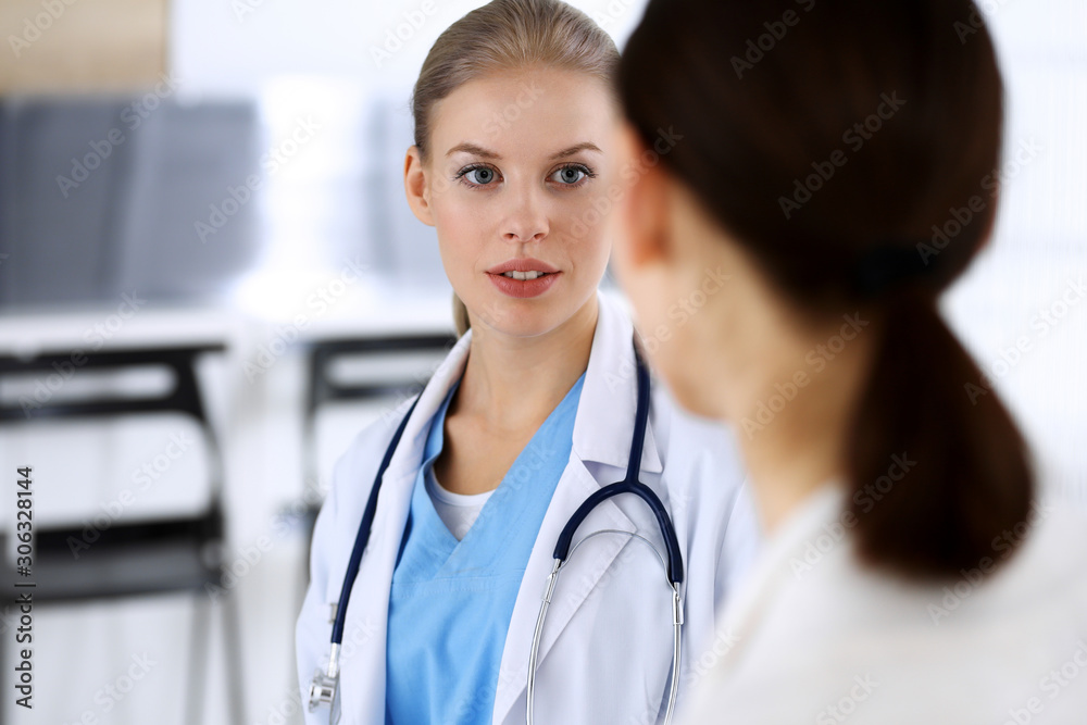 Doctor and patient during consultation. Physician at work filling up medication history record while sitting in emergency hospital, portrait shoot. Medicine and health care concept Doctor and patient during consultation. Physician at work filling up medication history record while sitting in emergency hospital, portrait shoot. Medicine and health care concept