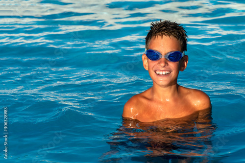 Happy smiling boy in water glasses in the pool. © alexytrener