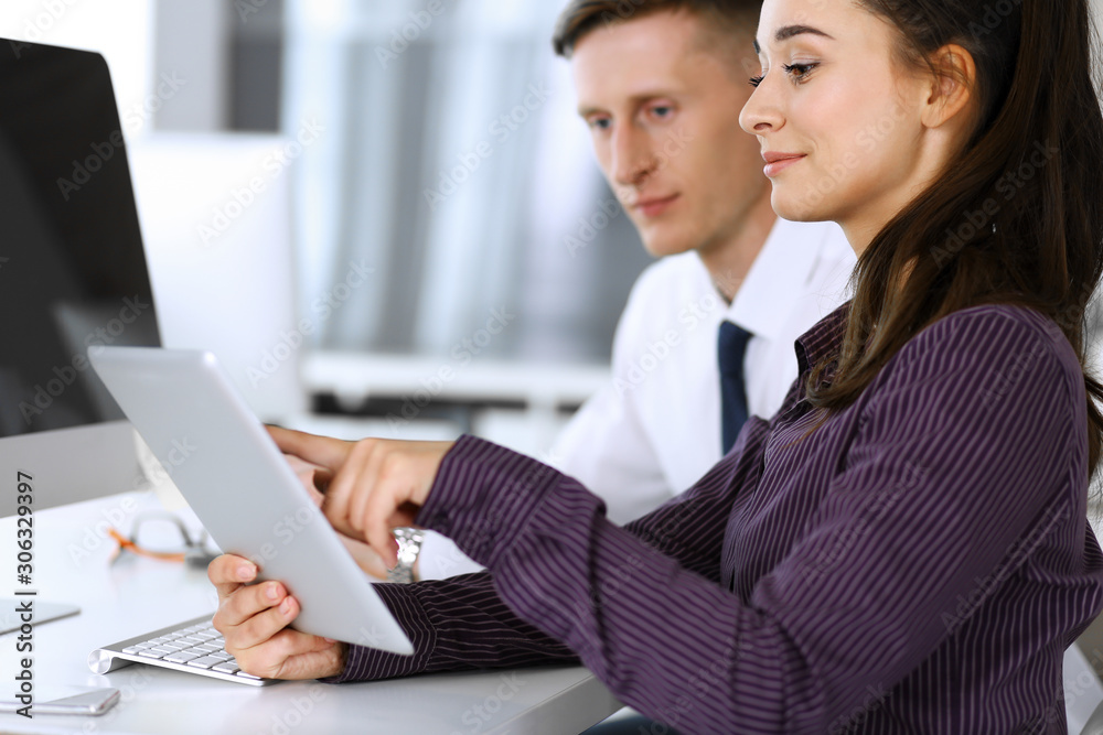 Business woman and man discussing questions while using computer at workplace in modern office. Teamwork, meeting and brainstorming concept Business woman and man discussing questions while using computer at workplace in modern office. Teamwork, meeting and brainstorming concept