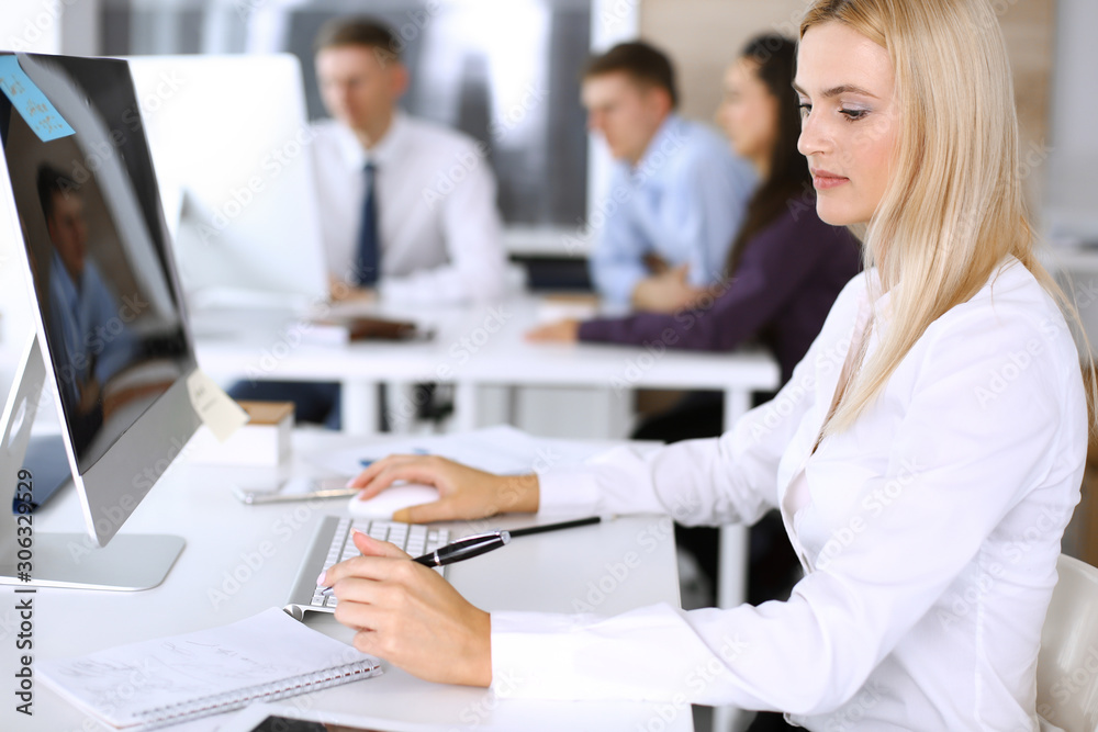 Business woman using computer at workplace in modern office. Secretary or female lawyer smiling and looks happy. Working for pleasure and success Business woman using computer at workplace in modern office. Secretary or female lawyer smiling and looks happy. Working for pleasure and success