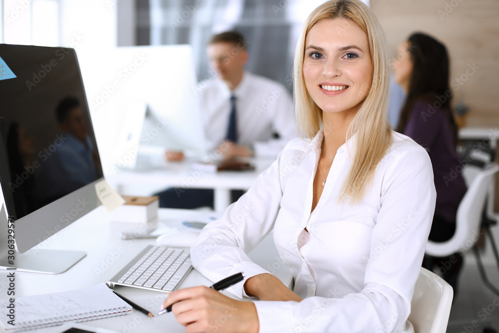 Business woman using computer at workplace in modern office. Secretary or female lawyer smiling and looks happy. Working for pleasure and success Business woman using computer at workplace in modern office. Secretary or female lawyer smiling and looks happy. Working for pleasure and success